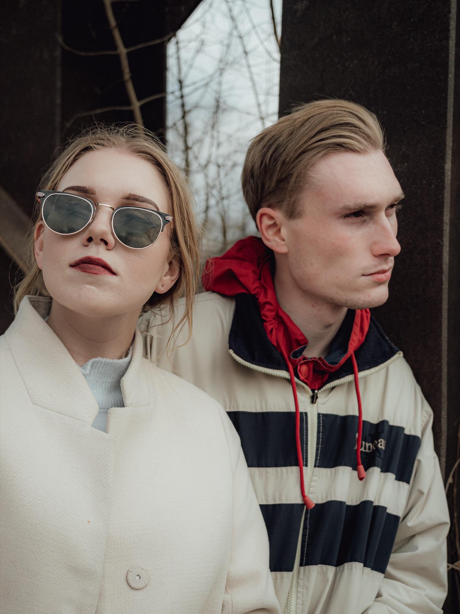 Editorial two-person look against weathered steel columns