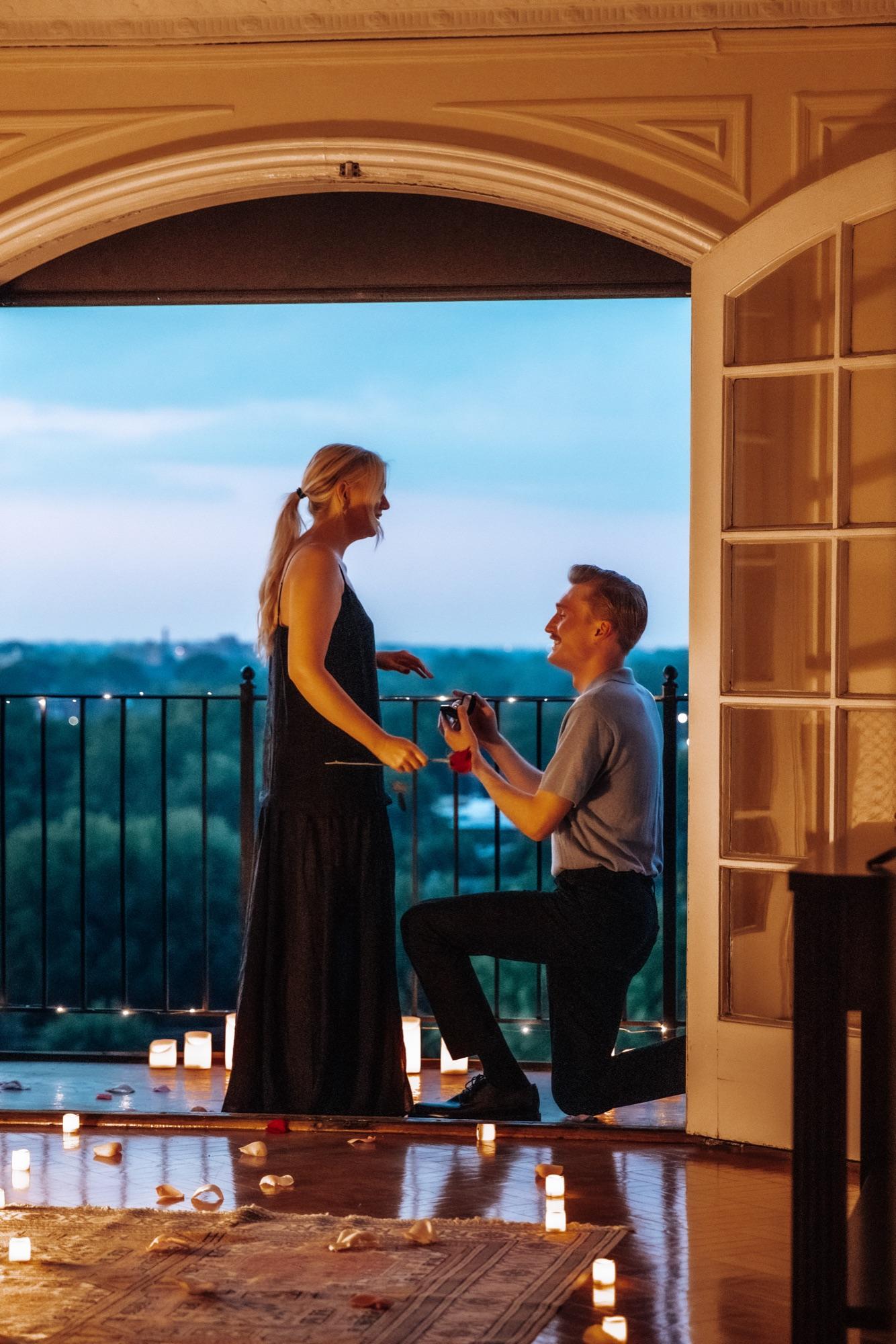 Down on one knee — blue-hour proposal on a balcony over the treetops