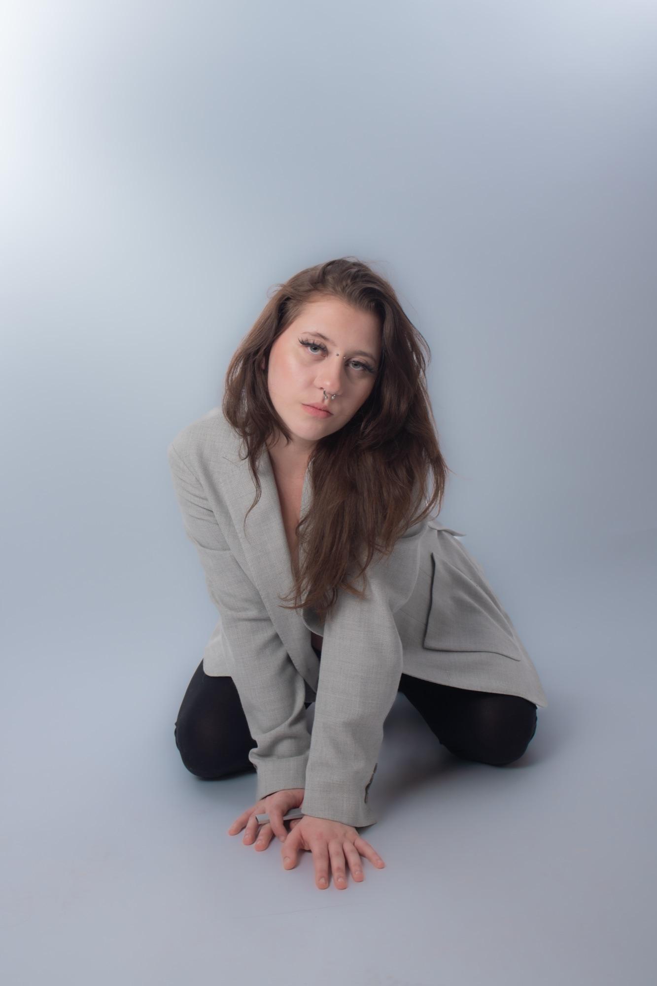 Editorial studio pose in an oversized blazer on seamless grey