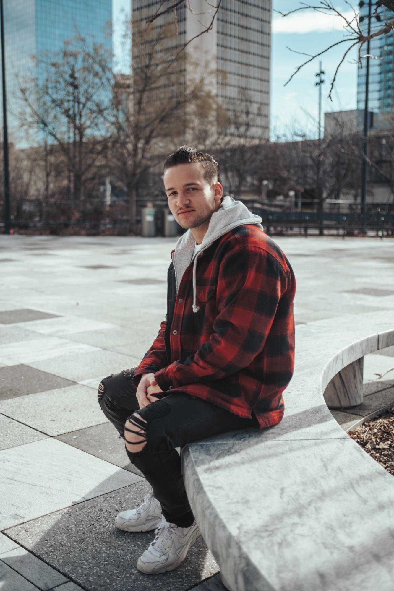 Seated portrait on a downtown St. Louis plaza in flannel and hoodie
