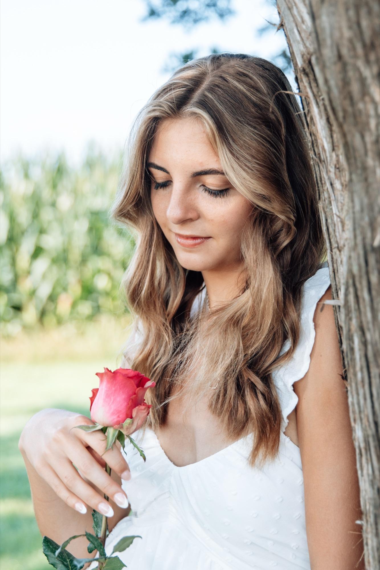 Senior portrait at the edge of a cornfield, hair backlit