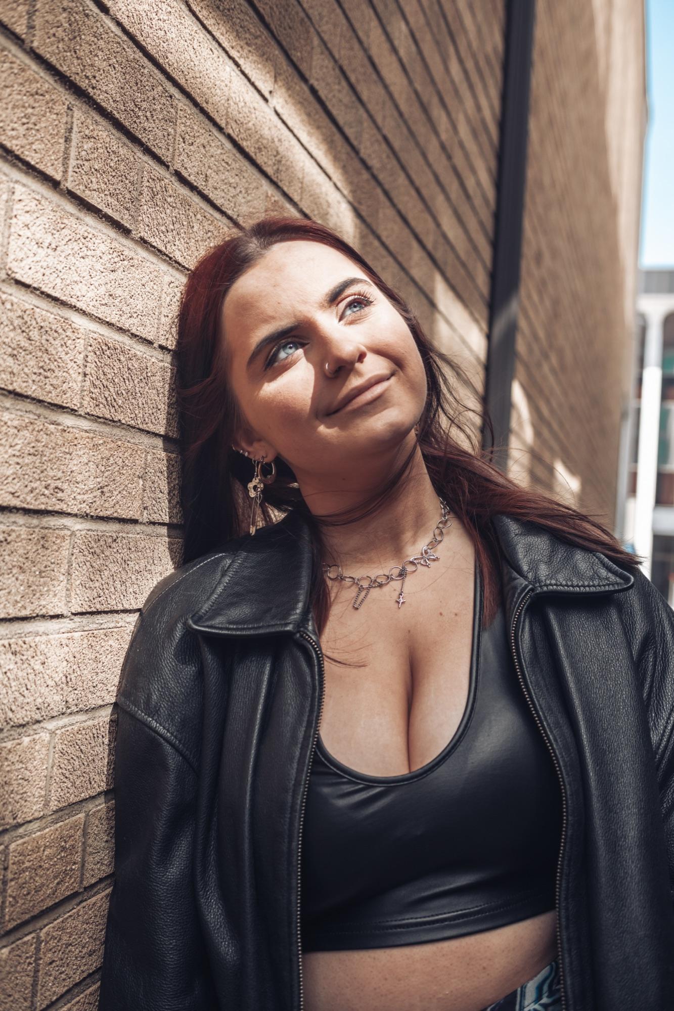 Senior portrait in a leather jacket, eyes closed to the sun