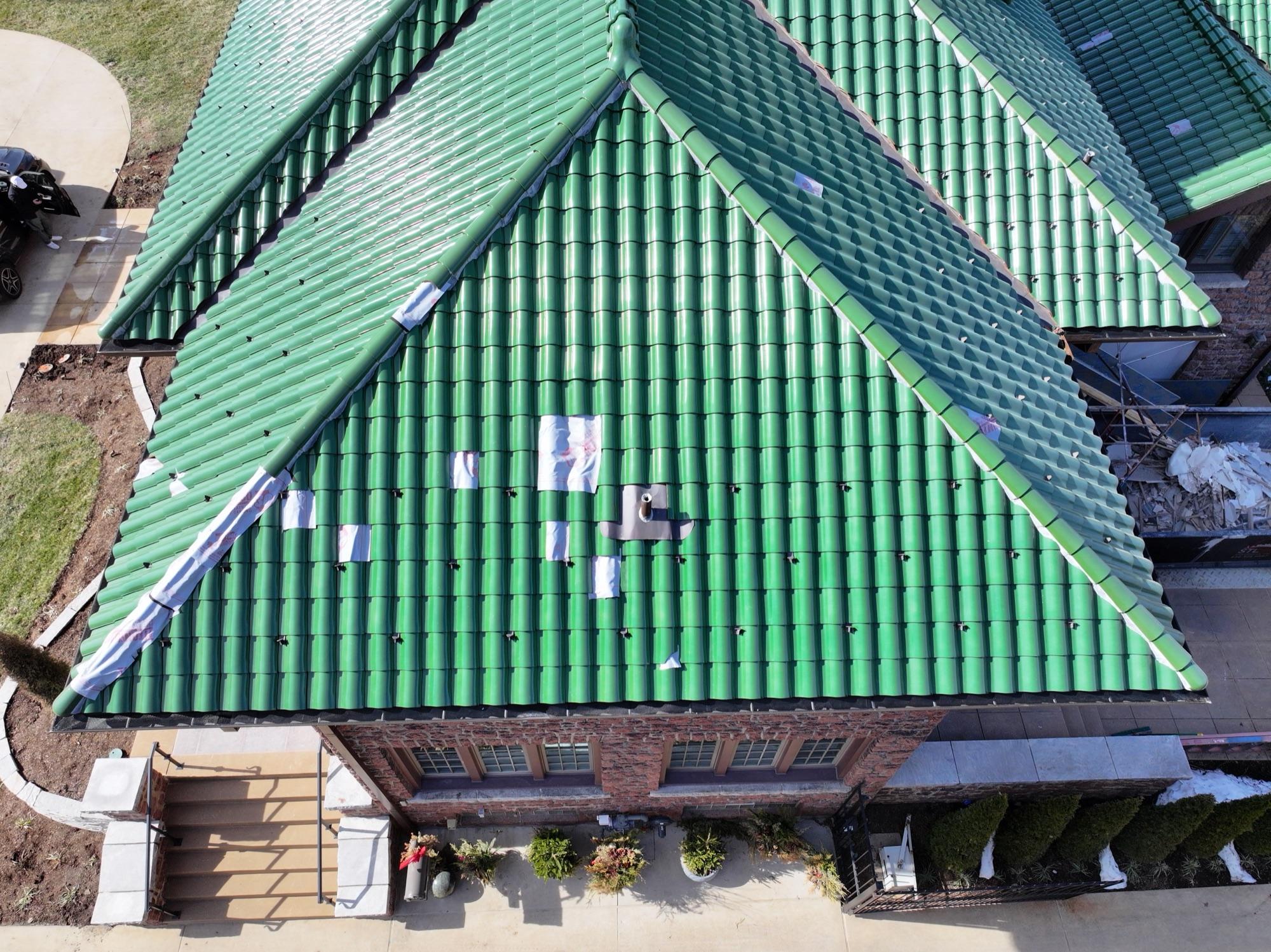 Top-down drone inspection of a glazed green tile roof mid-renovation, flashing and underlayment patches visible