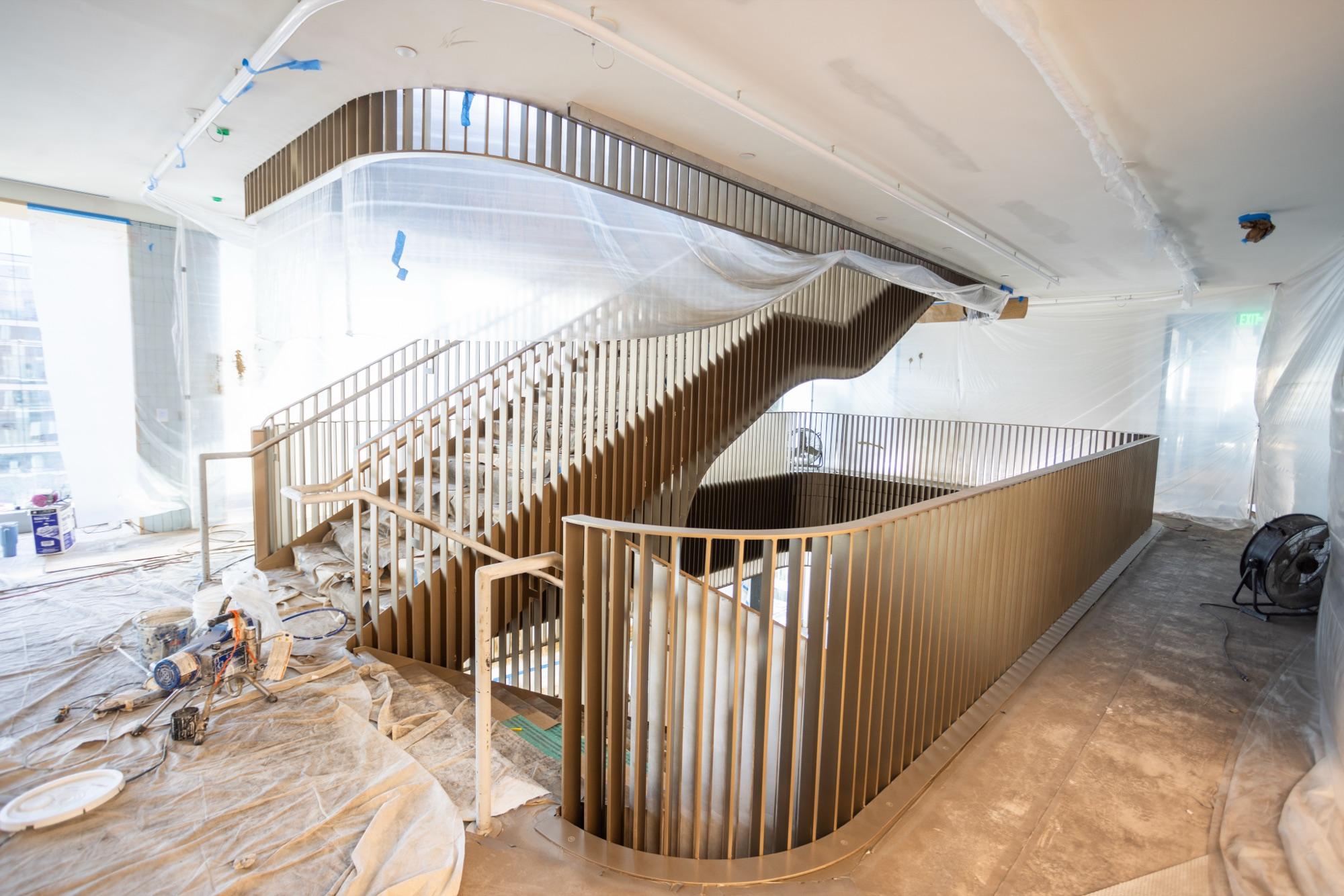 Sculptural wooden spiral stair rising through an office build-out