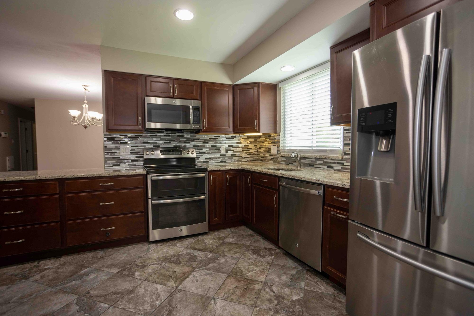 Listing photography — renovated kitchen with cherry cabinets, granite counters, and stainless appliances