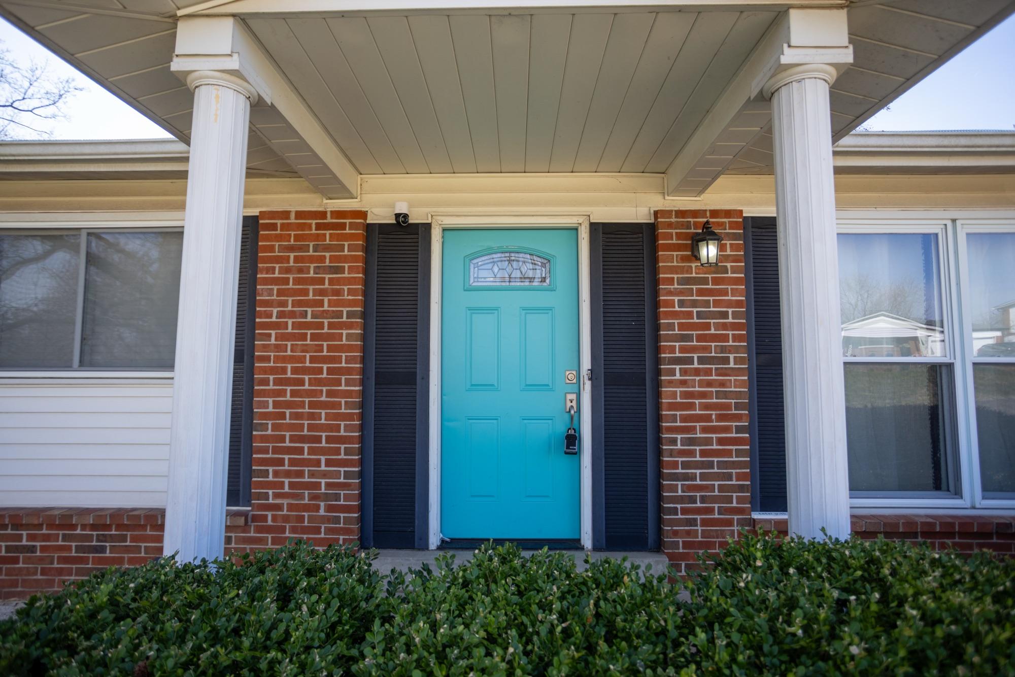Teal front door between brick columns — listing exterior detail