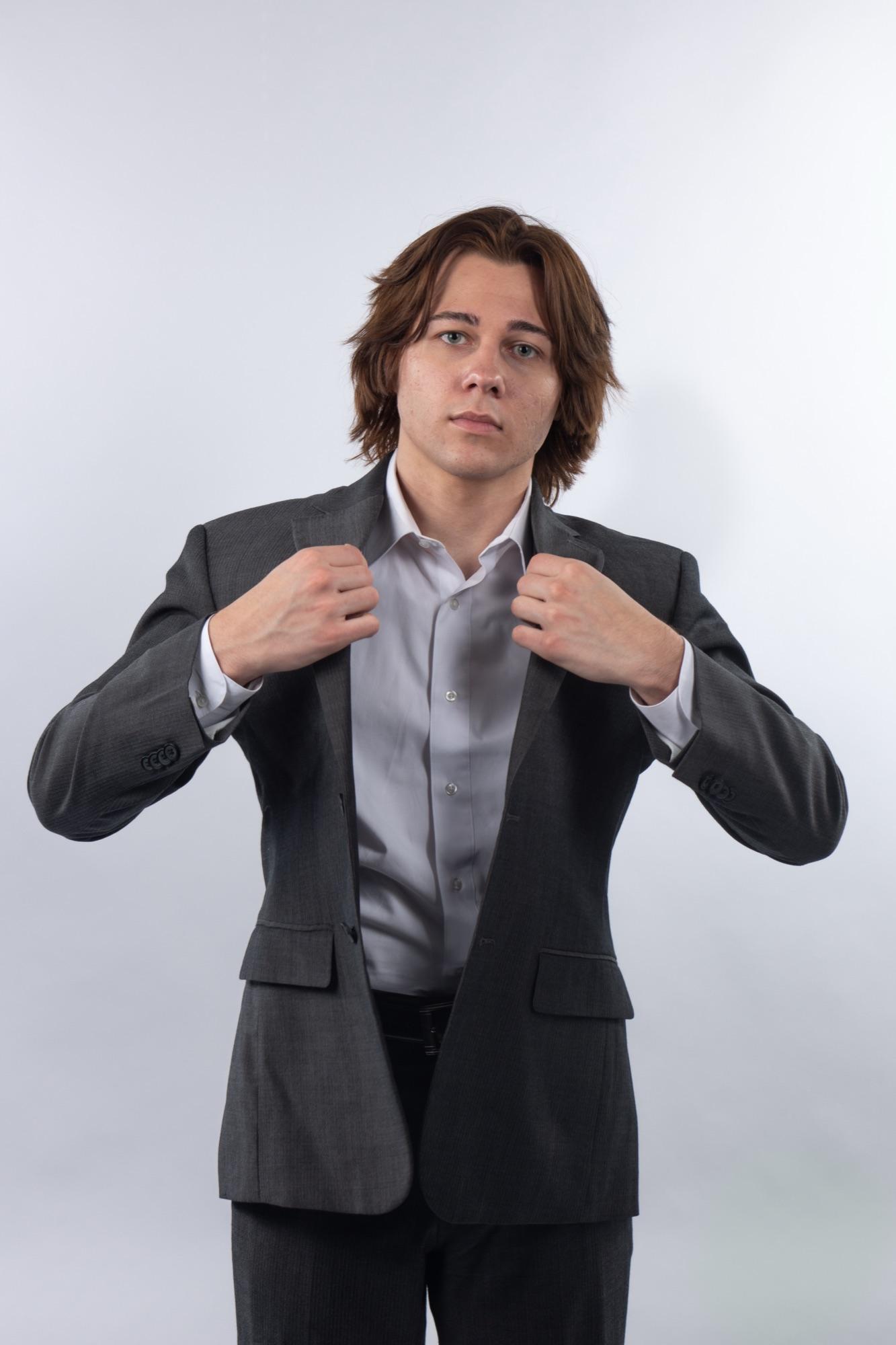 Actor-style headshot — adjusting the suit jacket mid-frame