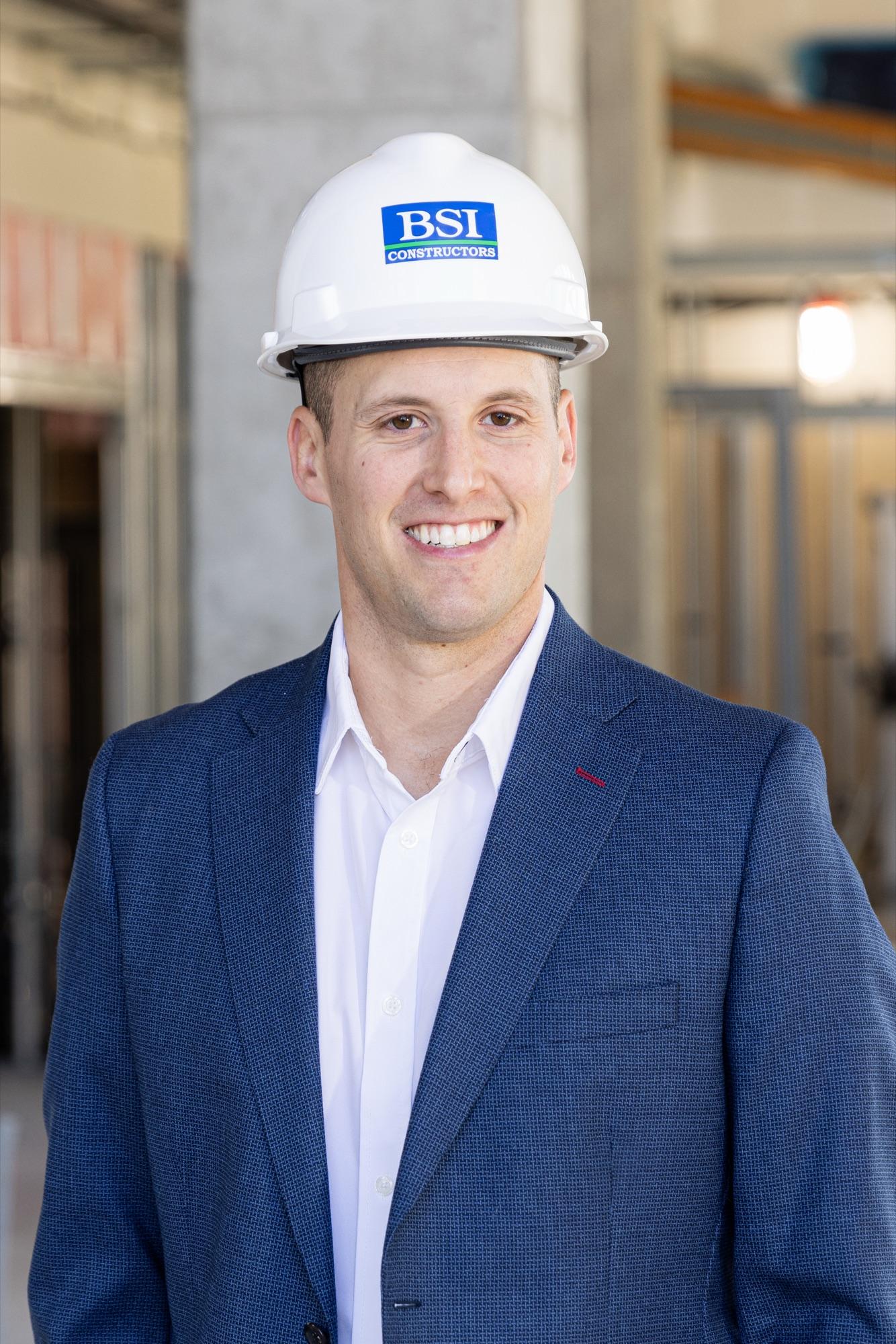 On-location headshot in a blue blazer, construction interior softened behind