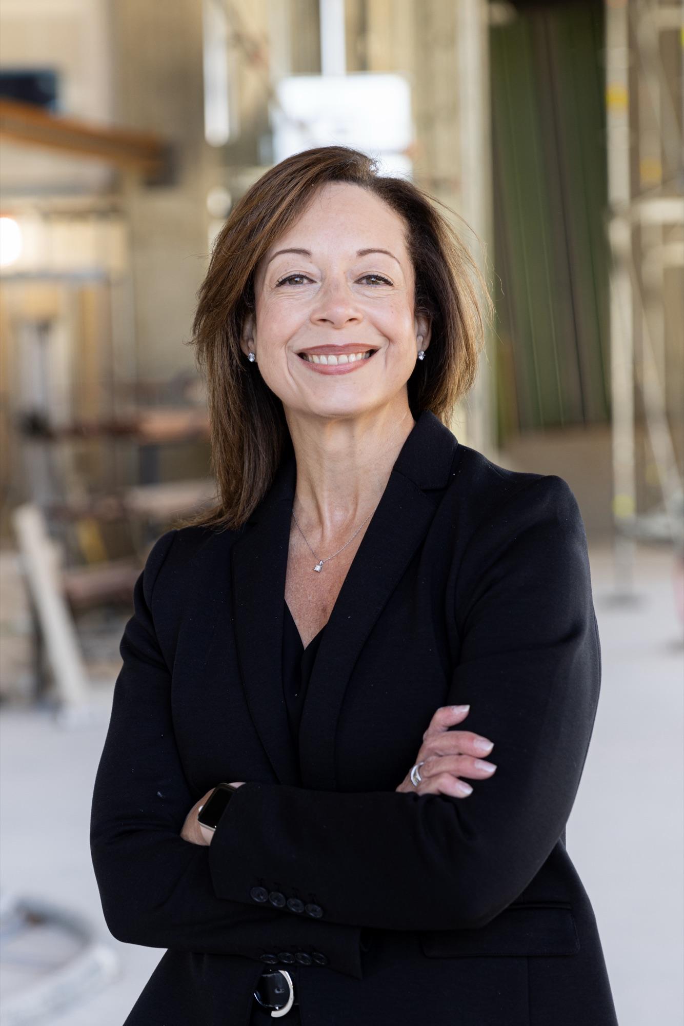 Executive headshot shot on the jobsite, black blazer against soft scaffold bokeh
